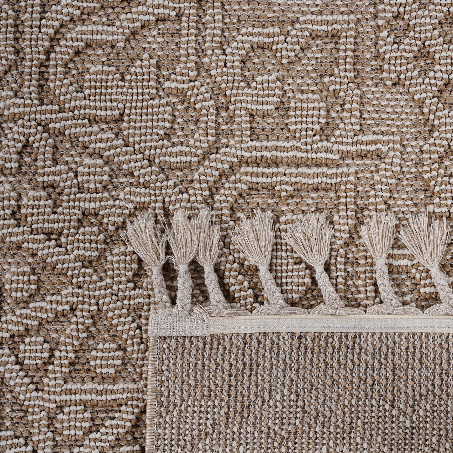 Closeup of a textured brown and cream woven rug with tasseled edges