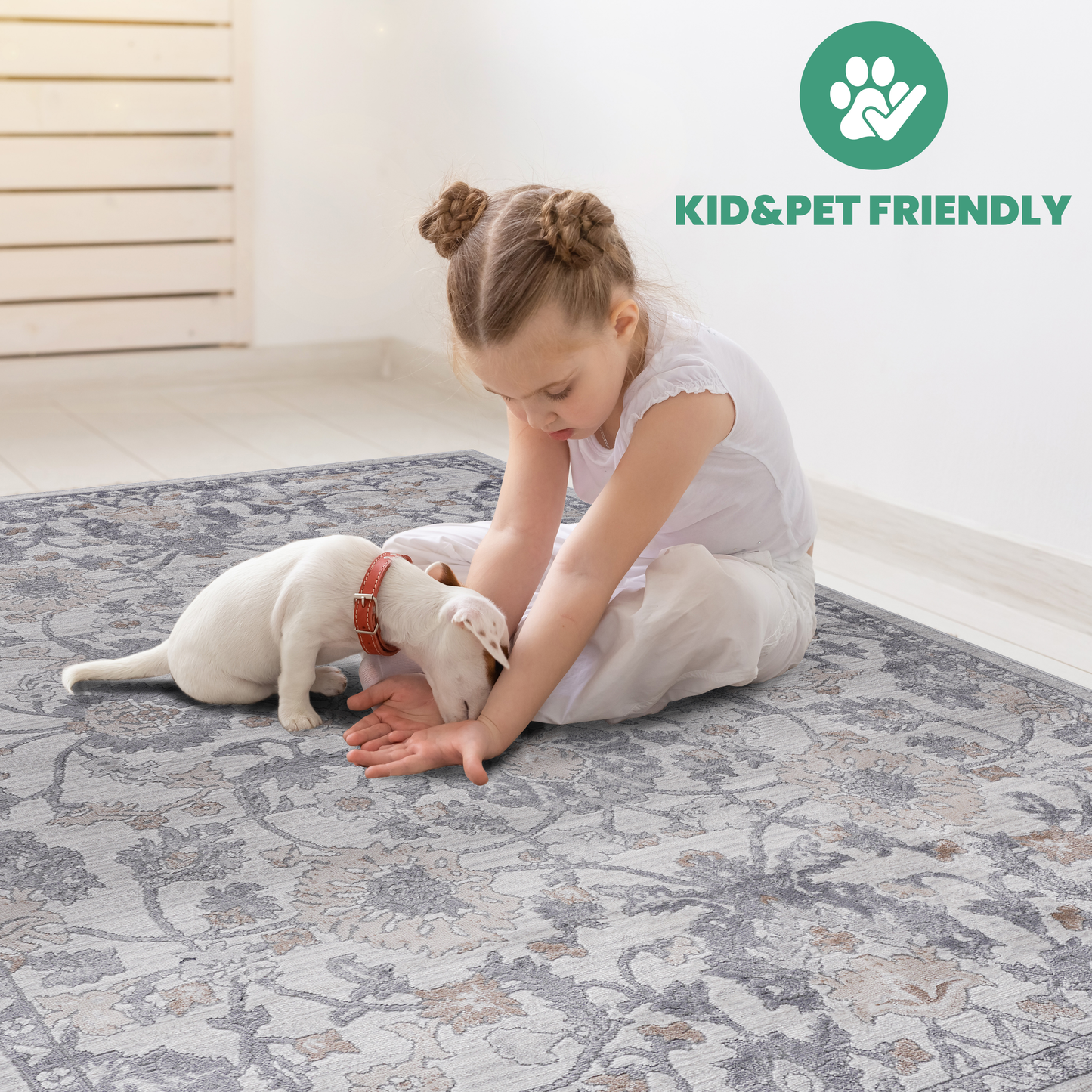Girl and puppy play on a grey and beige floral area rug