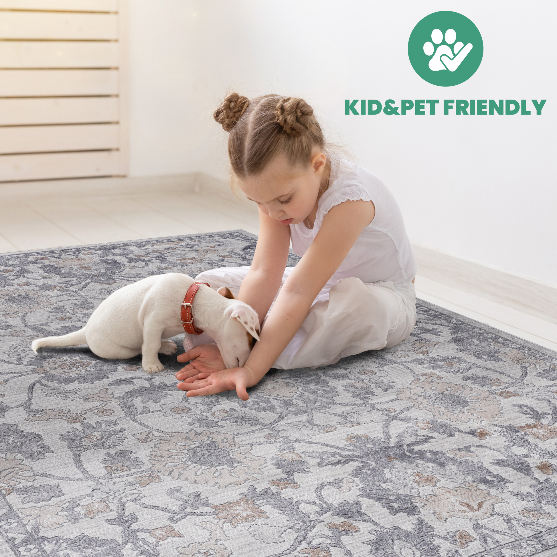 Girl and puppy play on a grey and beige floral area rug