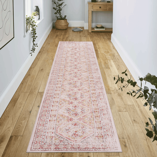 A vintage Persian runner rug in blush pink with red and gold diamond patterns for hallways