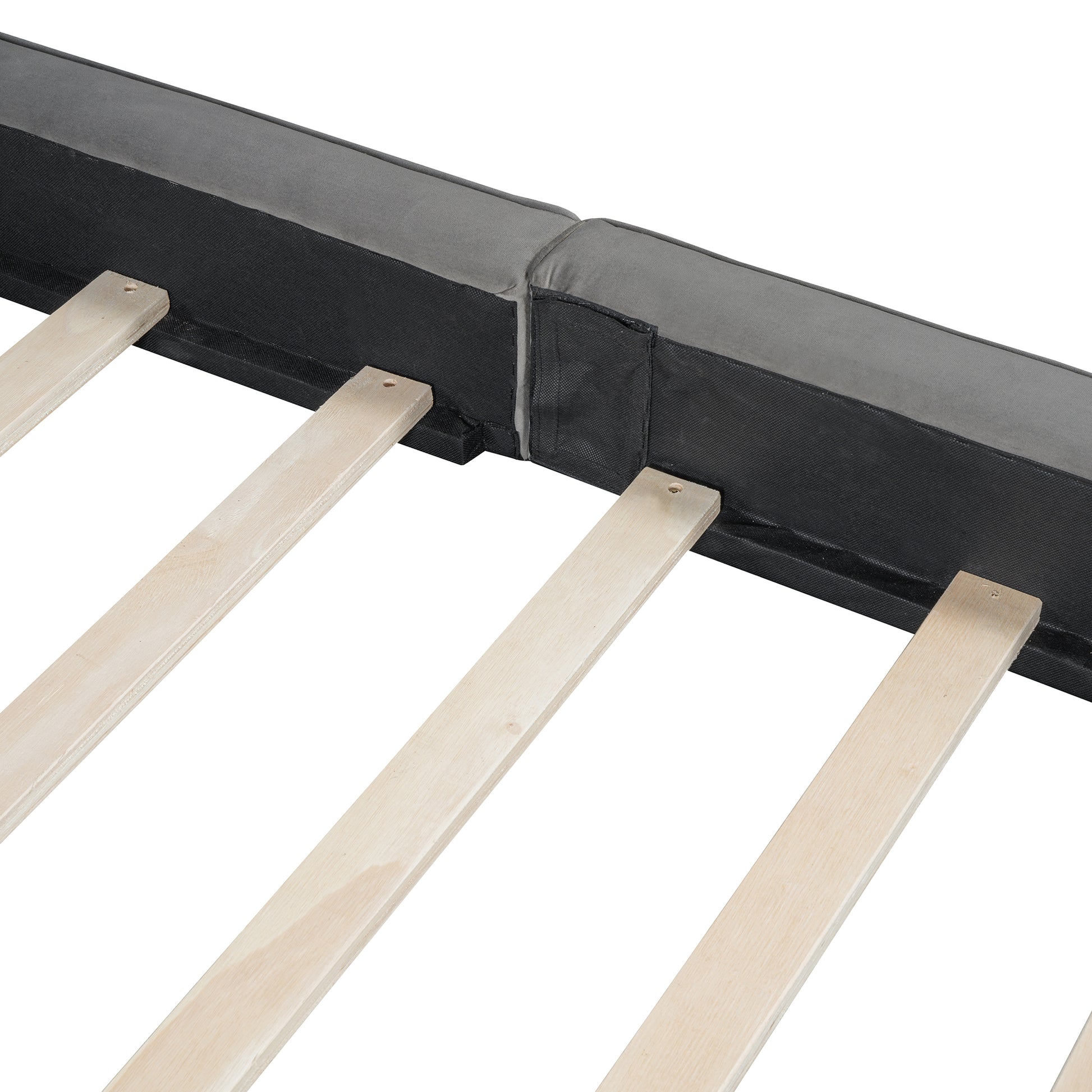 Closeup of a grey upholstered bed frame with wooden slats