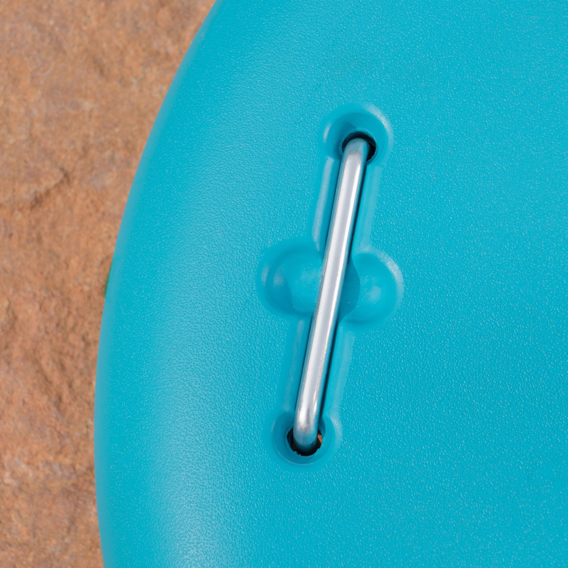 Bright blue textured plastic kayak paddle with metal connector on textured sand