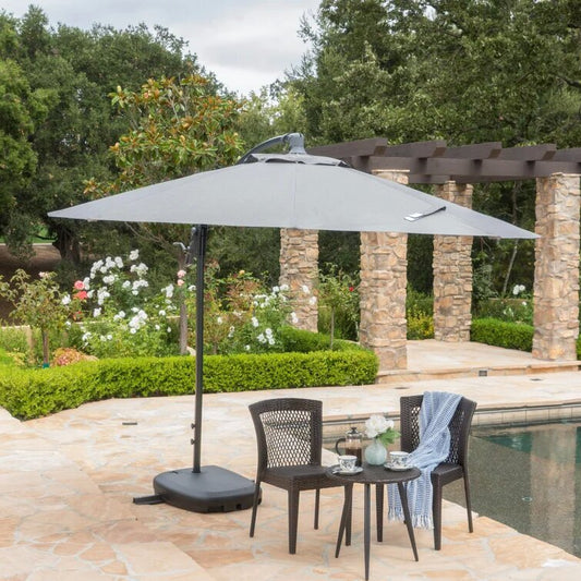 Gray rectangular cantilever patio umbrella with black base providing shade by a pool