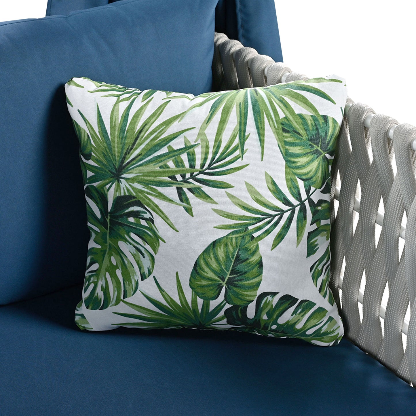 Decorative throw pillow with green tropical leaf print on white fabric