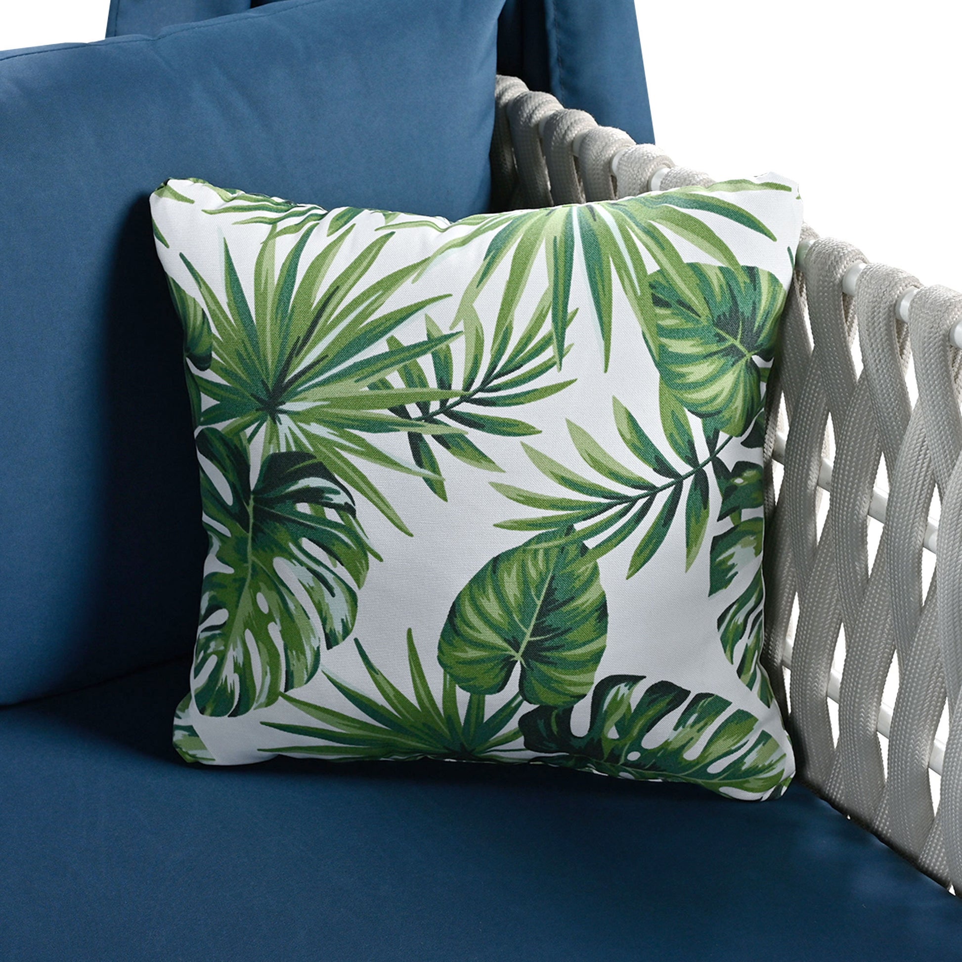 Decorative throw pillow with green tropical leaf print on white fabric