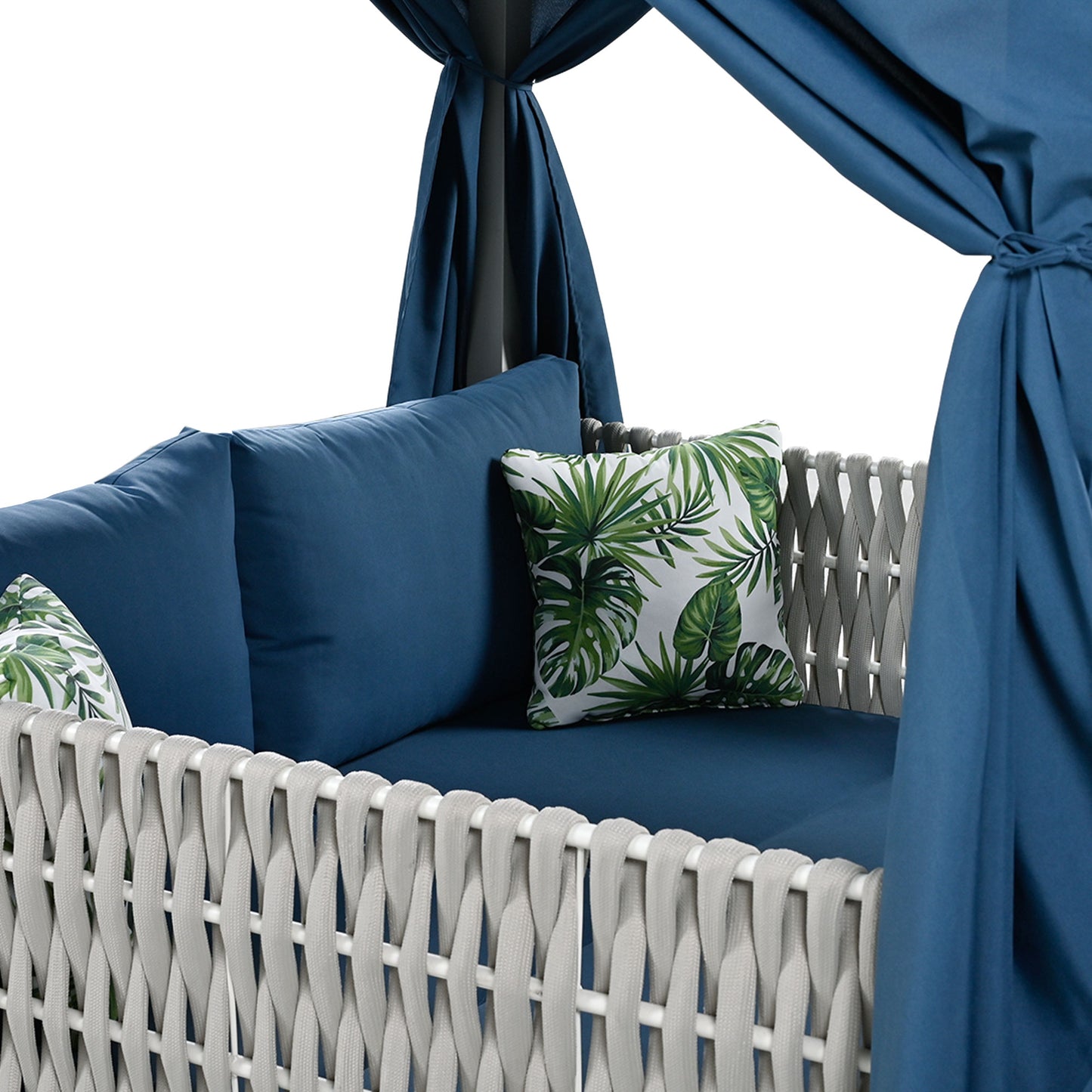 Navy blue outdoor daybed with tropical leaf pattern accent pillows and grey woven frame