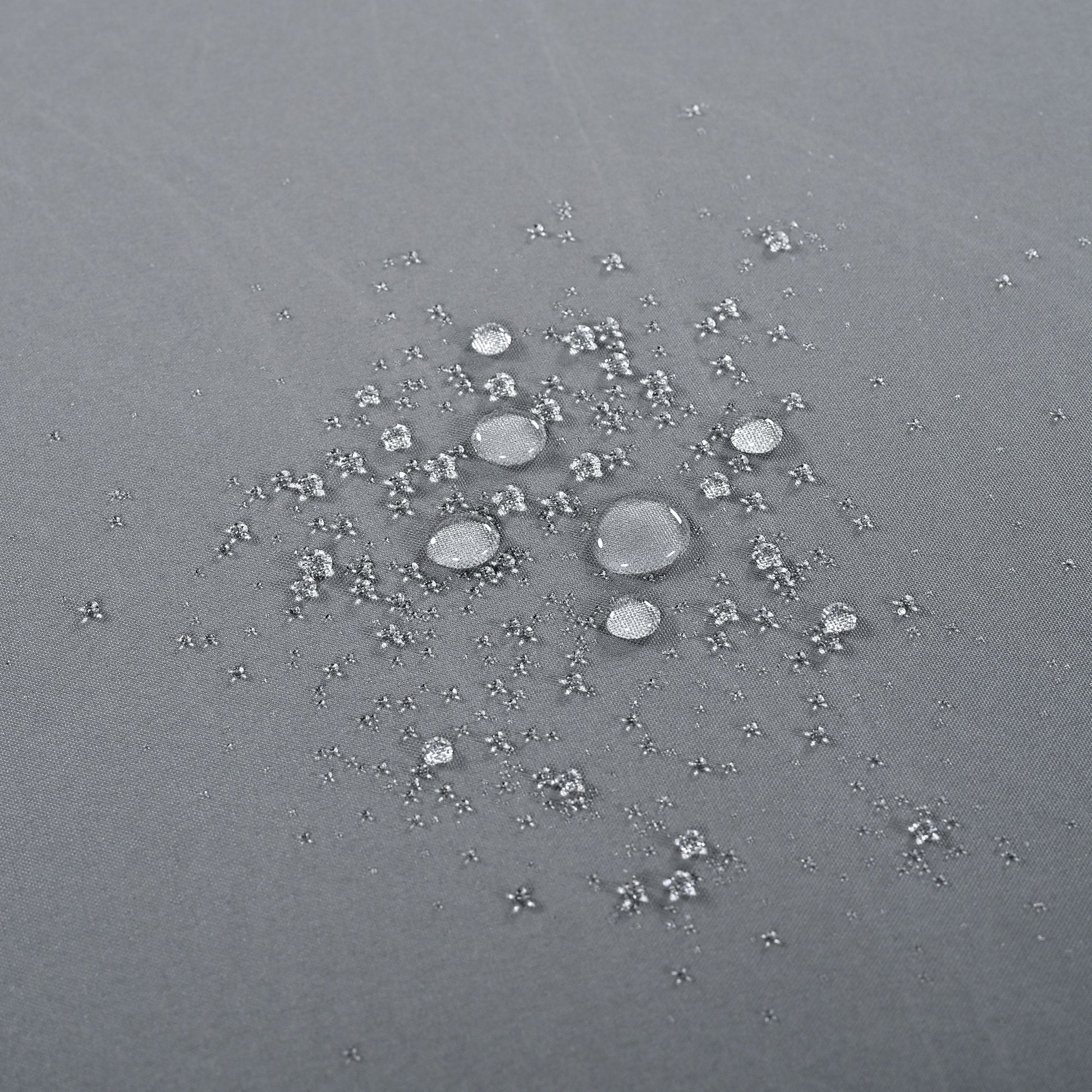 Closeup of water beads on a grey waterproof fabric texture