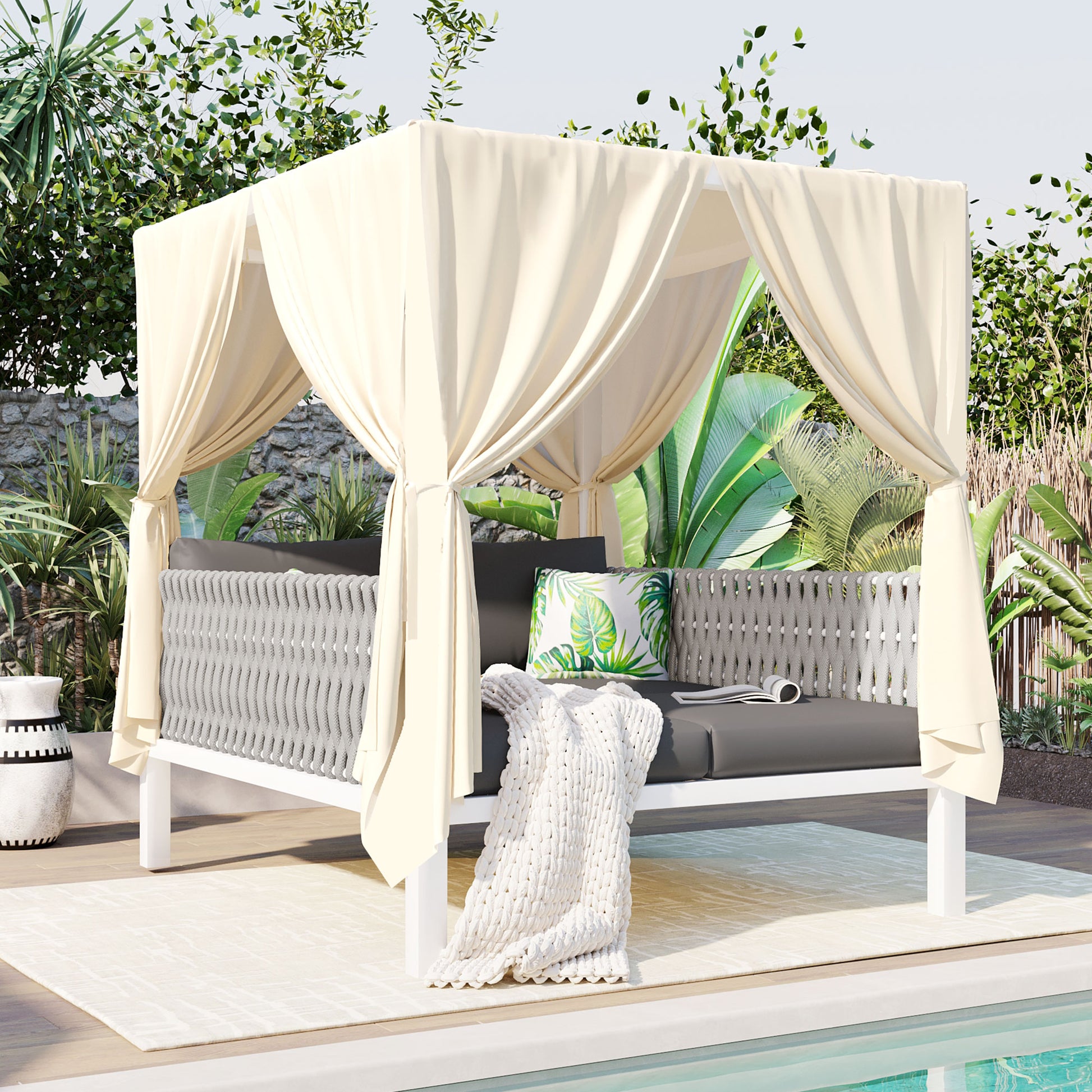 Cream canopy daybed with grey woven sides featuring a tropical leaf pillow and white throw