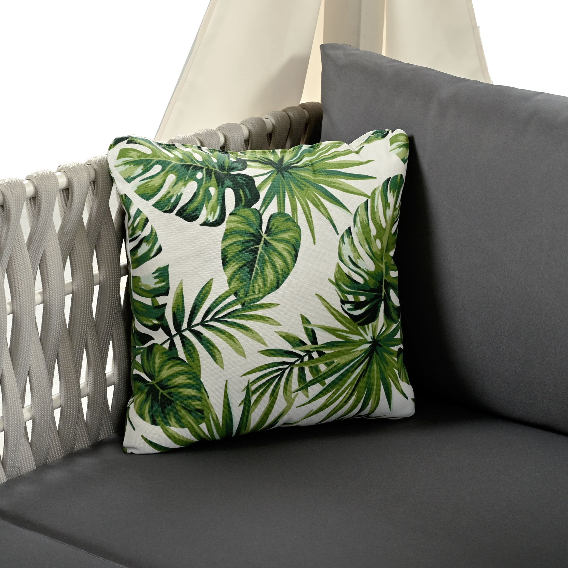 Decorative outdoor pillow with tropical monstera leaf print on white background