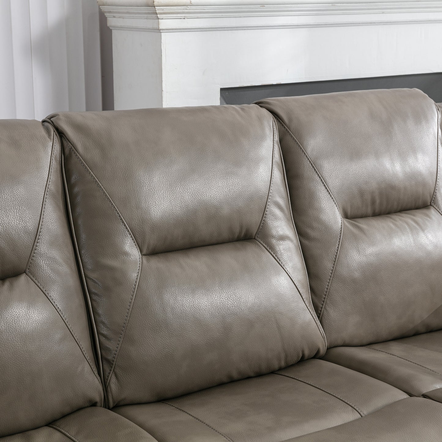Close up of a plush taupe leather reclining sofa highlighting stitch detail and comfortable cushioning