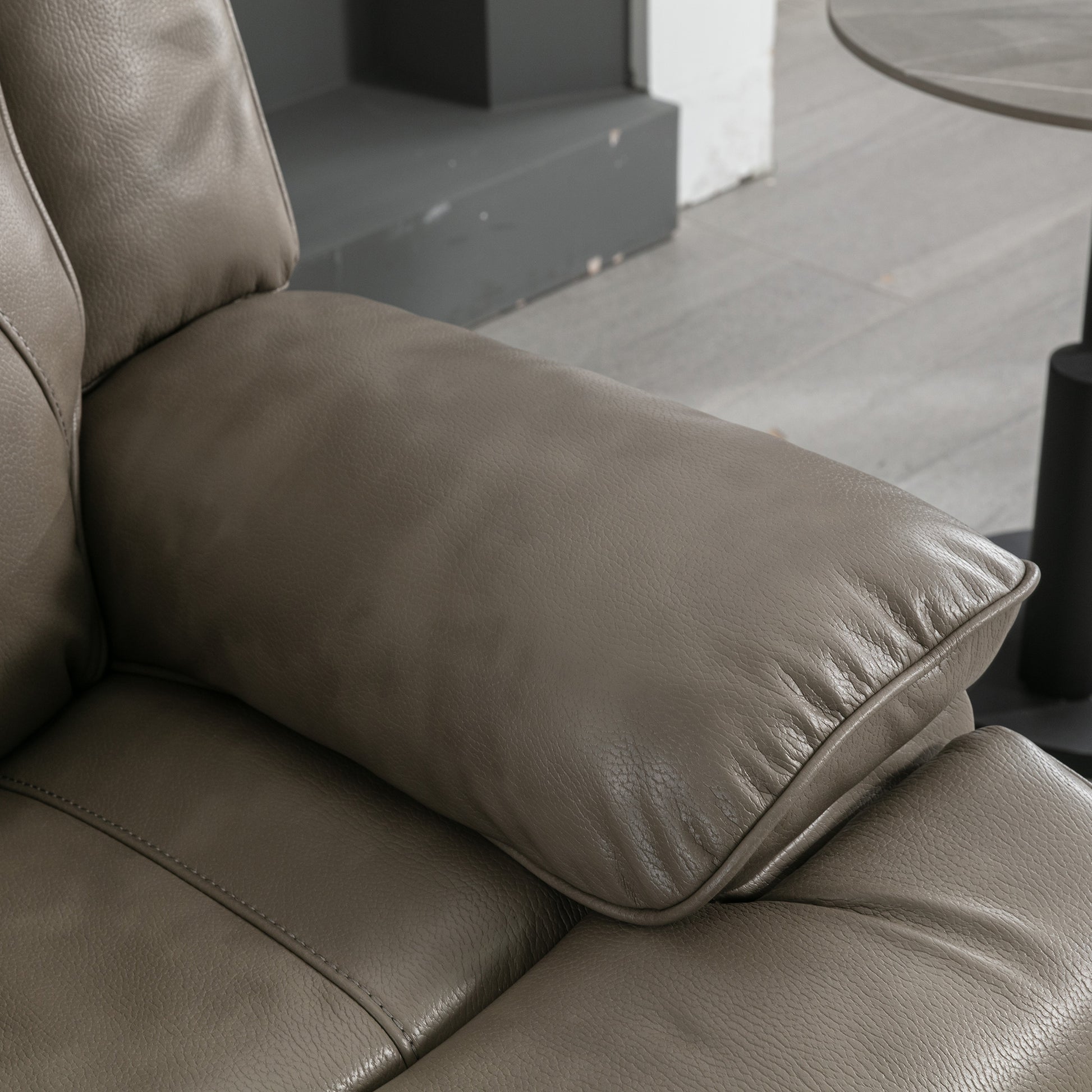 Closeup of a taupe leather recliner armrest with detailed stitching and a plush cushion