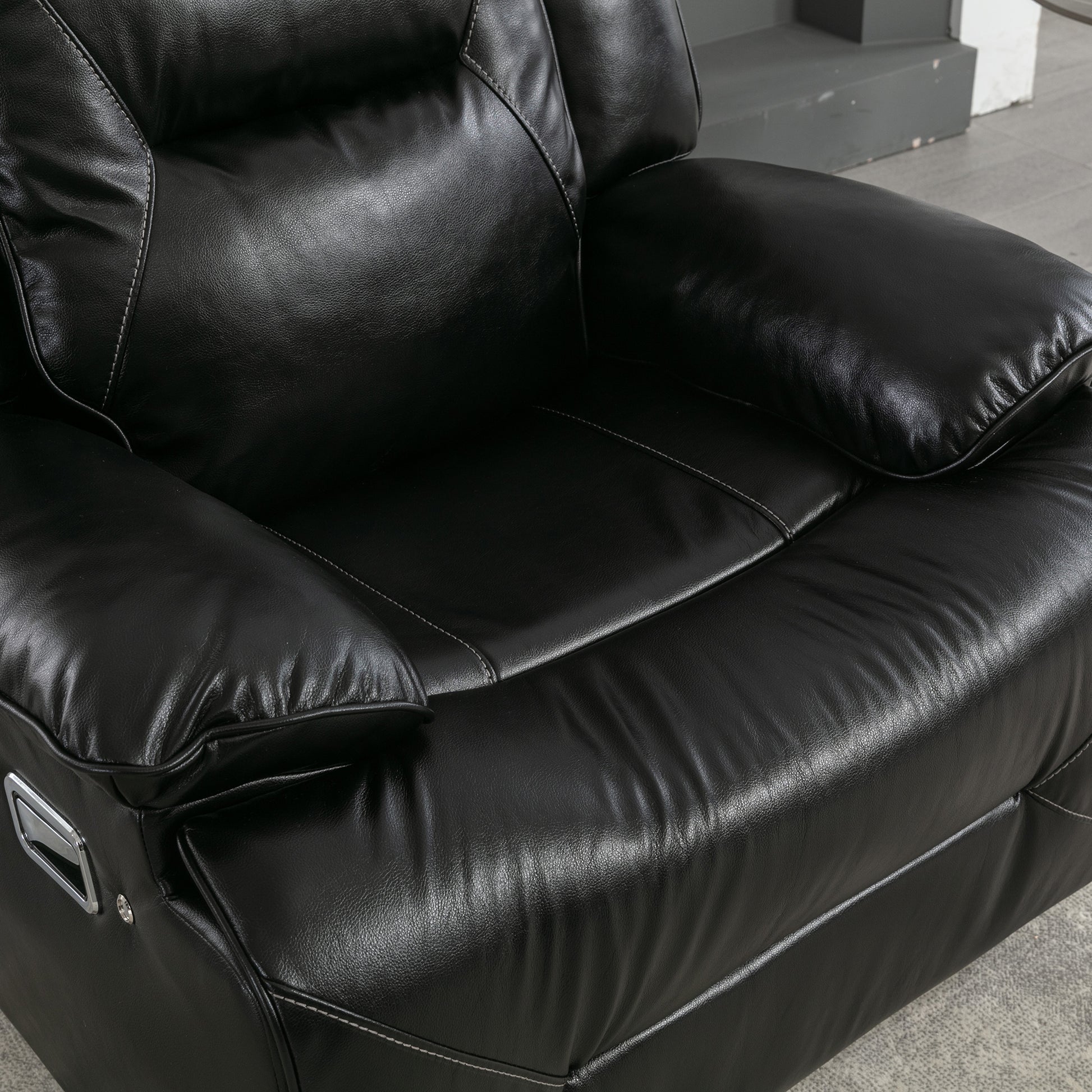 Closeup of plush black leather recliner seat with white stitching detail