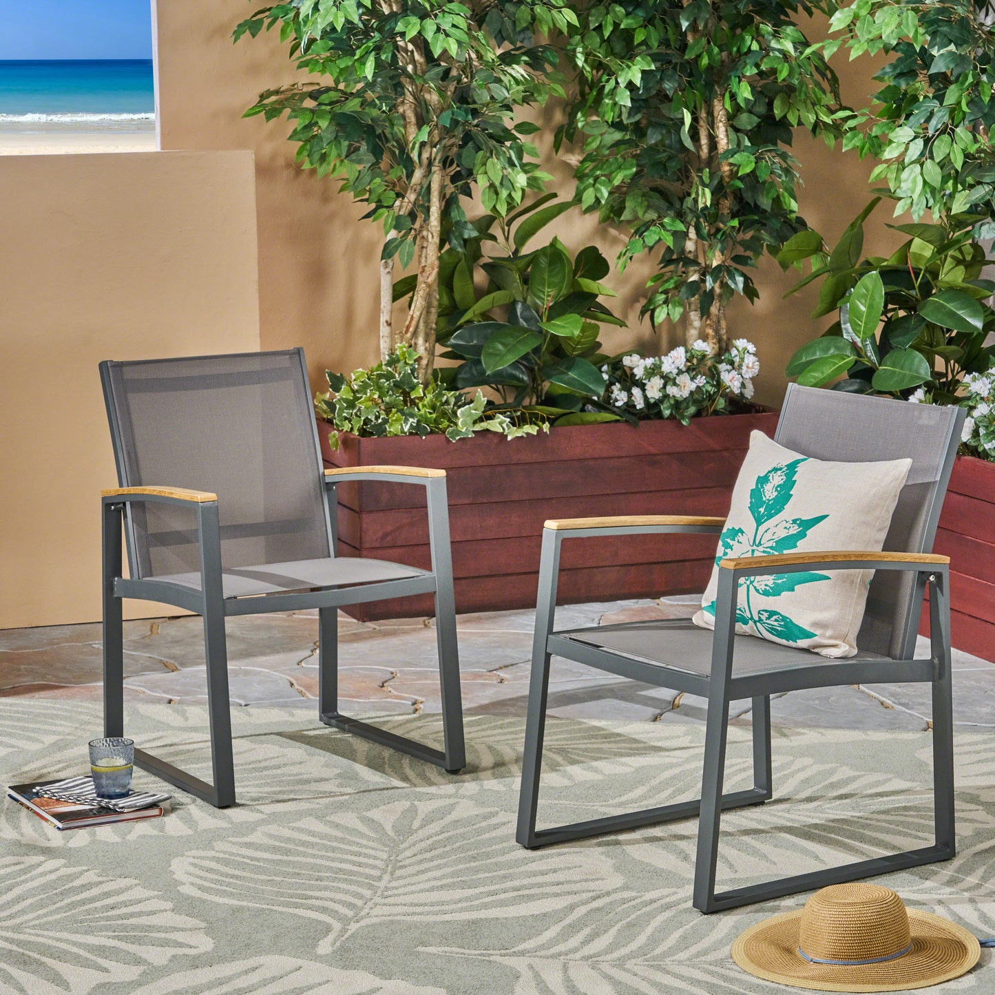 Two grey metal outdoor dining chairs with wood armrests and patterned cushions