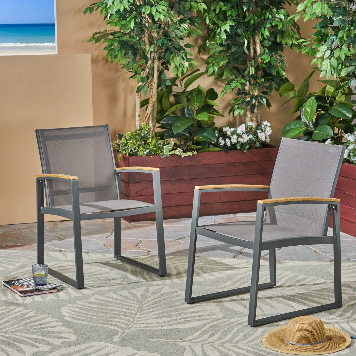 Two grey metal outdoor chairs with wooden armrests on a patio rug