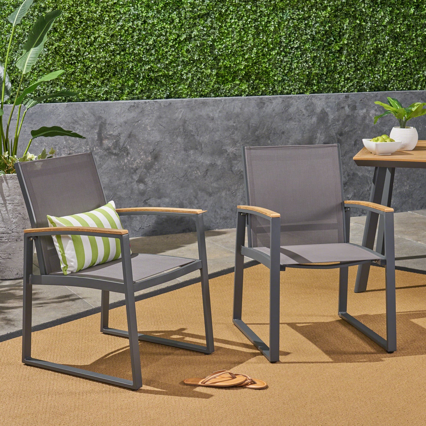 Gray mesh outdoor chair with wooden armrests and green striped pillow