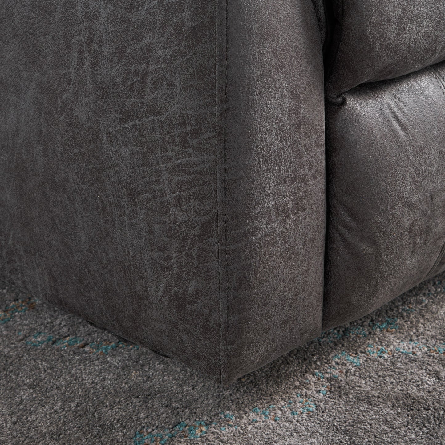 Dark grey faux leather corner of a plush armchair showing stitched seams and textured finish