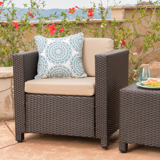 Dark brown wicker armchair with a light beige cushion and blue patterned pillow