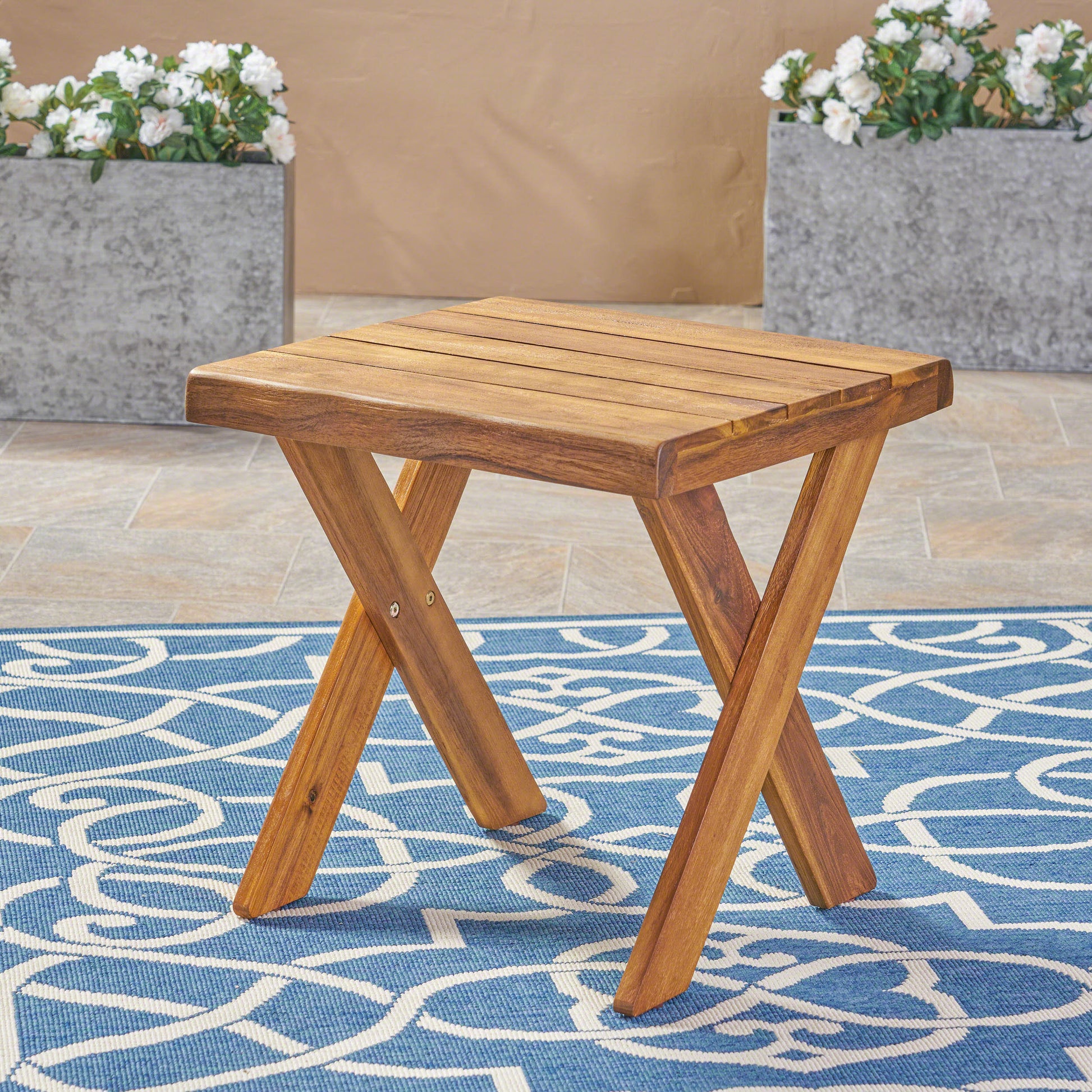 Acacia wood side table with a slatted top and Xshaped legs perfect for outdoor patios