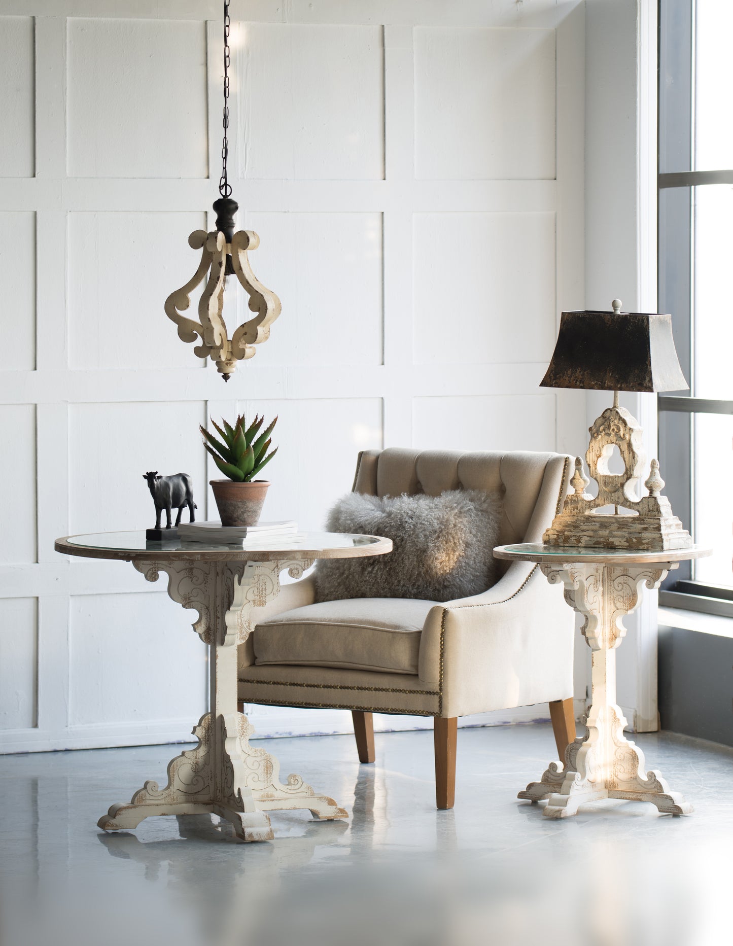 Ornate carved wood chandelier with distressed cream finish adding rustic charm to interiors