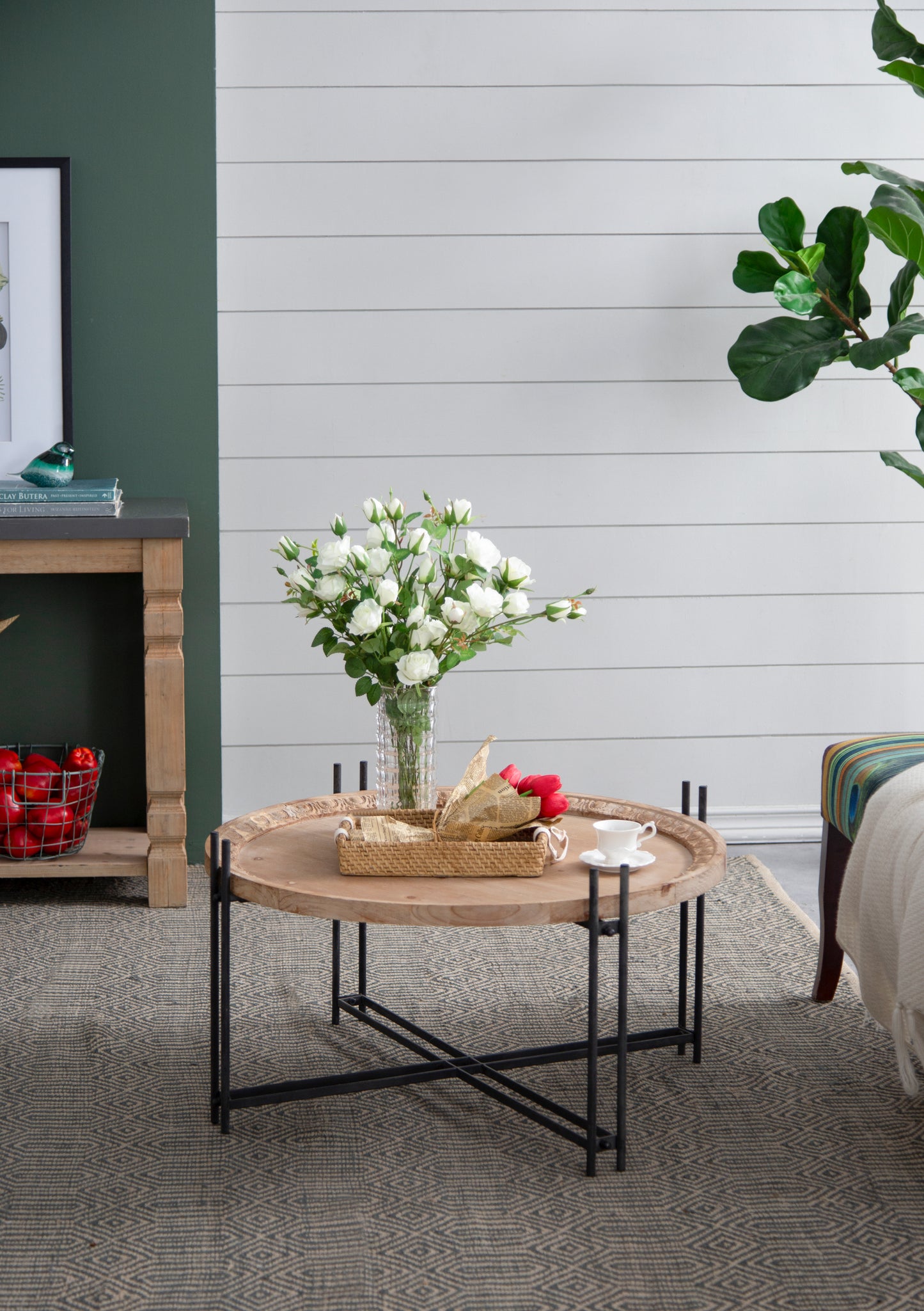 Round wooden coffee table with black metal legs and carved details