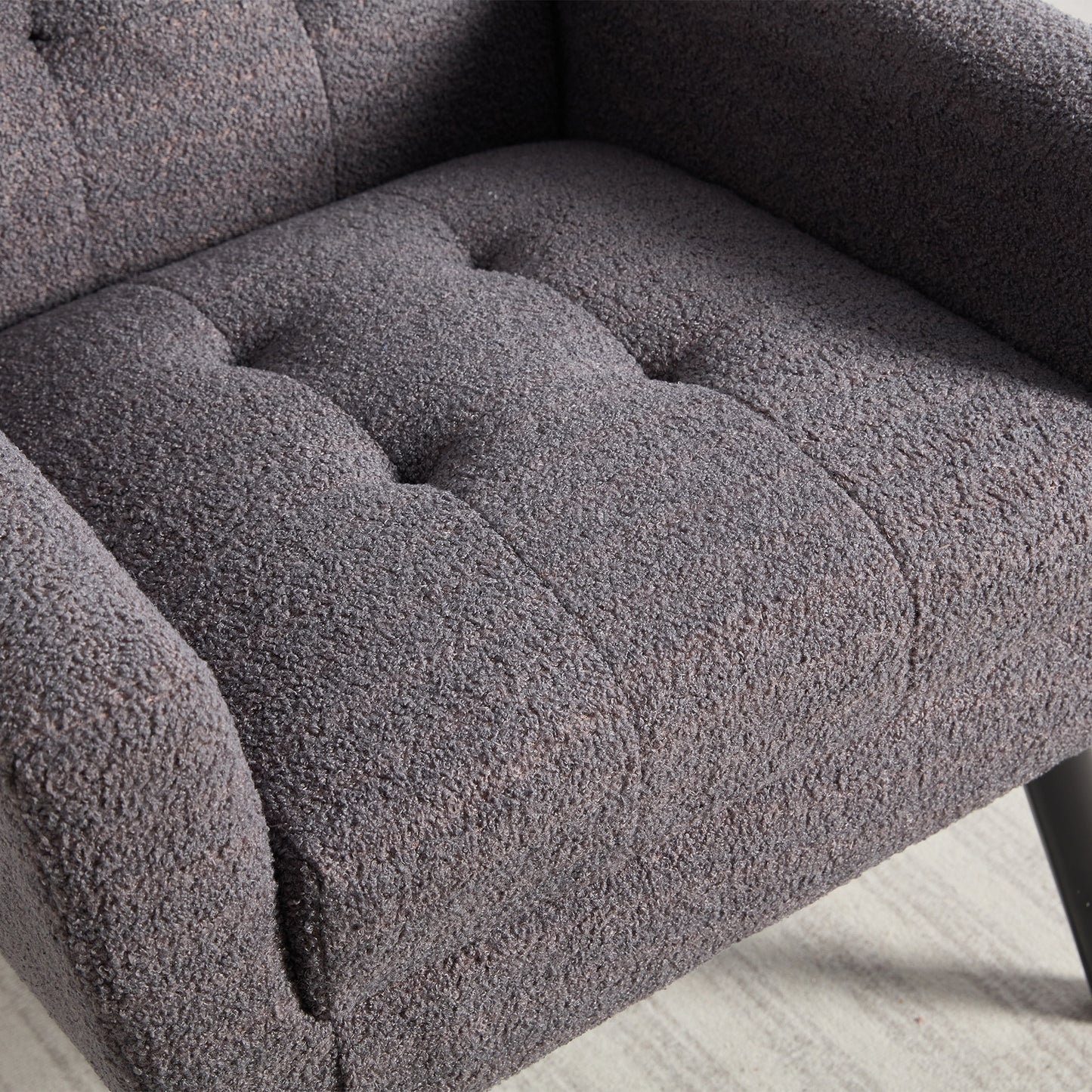 Closeup of a textured dark grey armchair with tufted seat cushions perfect for a cozy living room
