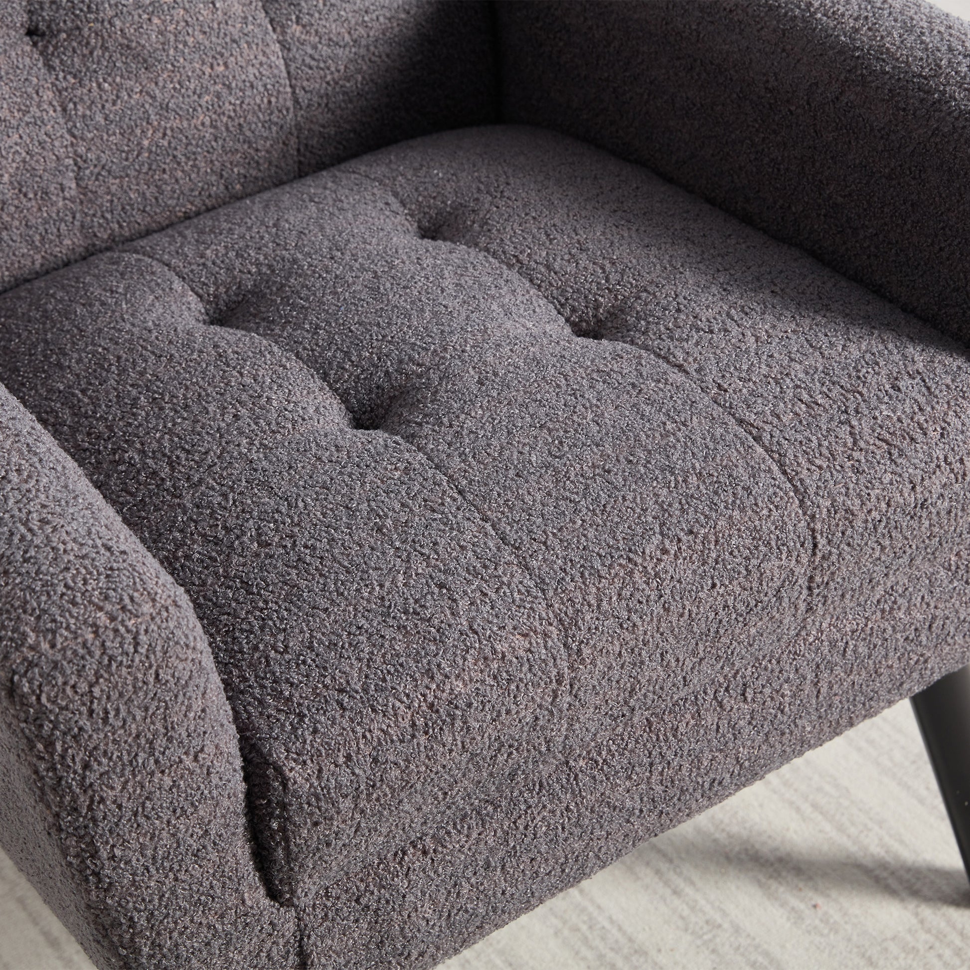 Closeup of a textured dark grey armchair with tufted seat cushions perfect for a cozy living room