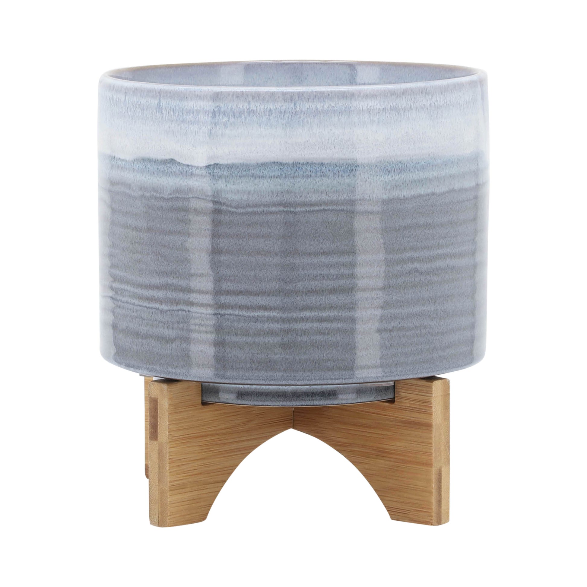 Glazed ceramic planter with bluegray gradient supported by a wooden stand for indoor plants