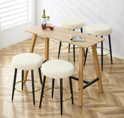 Four fluffy white bar stools with gold footrests and black legs surround a light wood bar table
