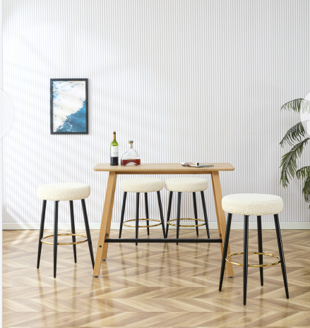 Four cream boucle bar stools with black metal legs and gold footrests arranged around a wooden bar table
