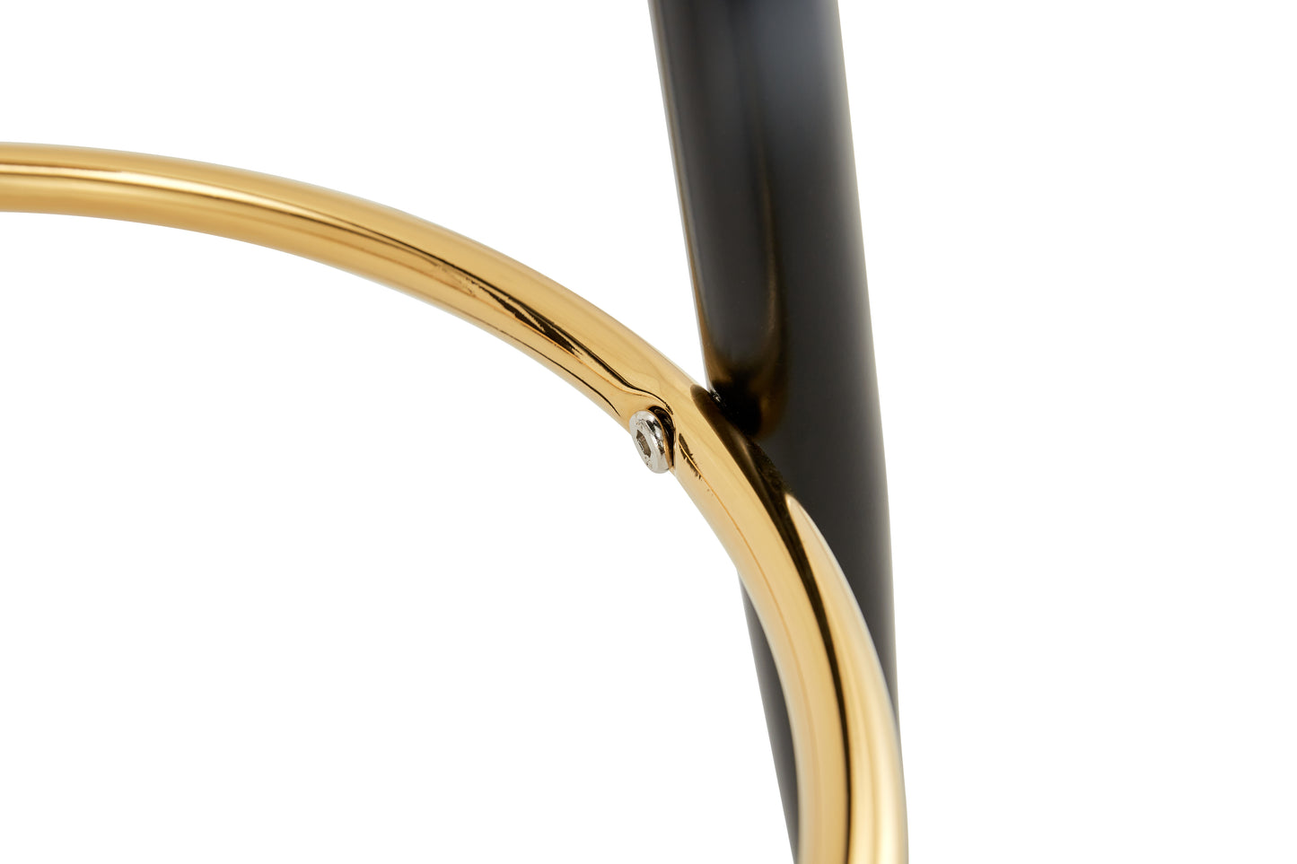 Closeup of polished gold footrest ring and black metal leg of a modern stool
