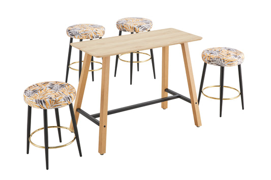 Light wood bar table with four black stools featuring tropical leaf print cushions and gold footrests