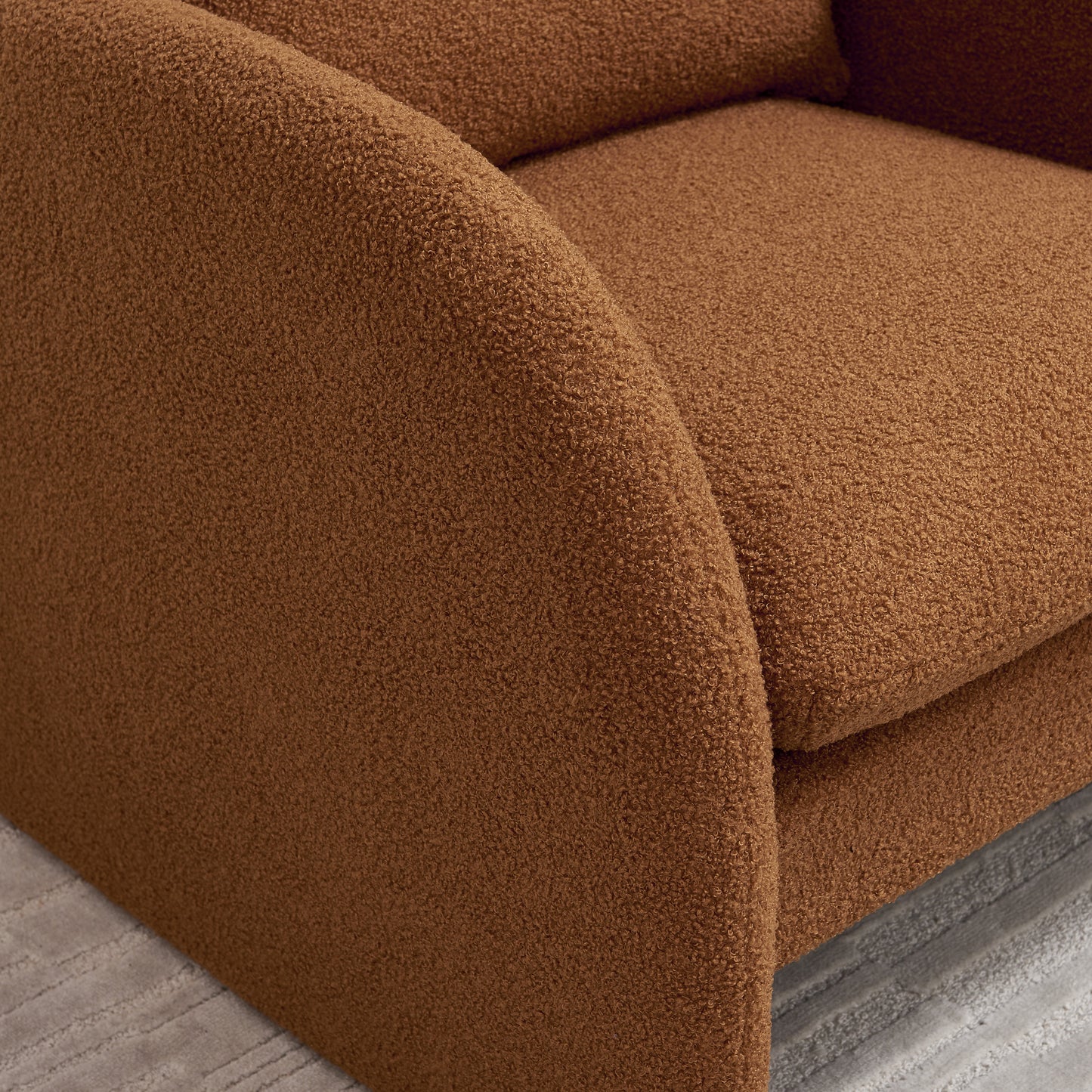 Closeup of plush terracotta boucl fabric on a modern armchair showcasing its textured weave