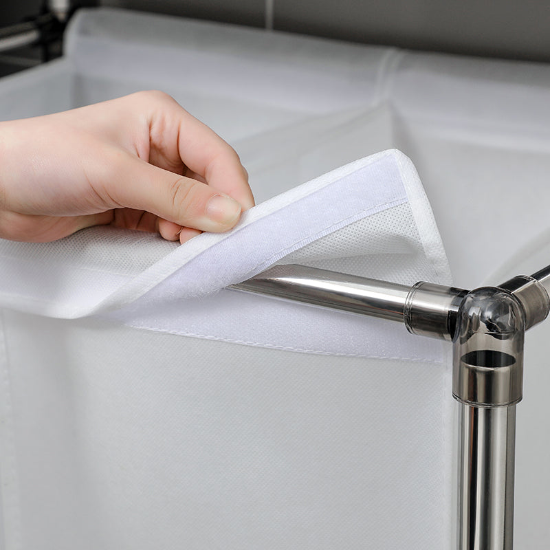 Close up of a hand securing white fabric liner with velcro onto a metal laundry basket frame