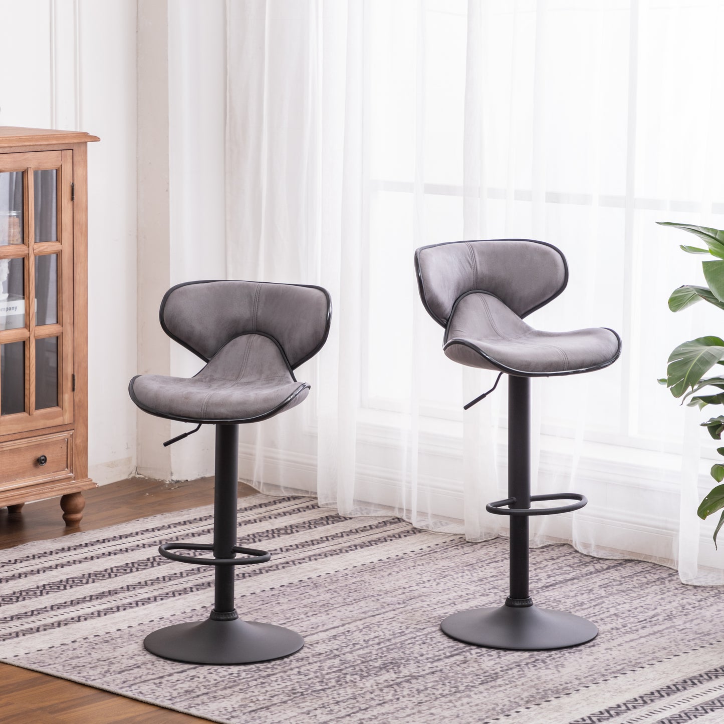 Two gray faux leather bar stools with adjustable height and black metal bases