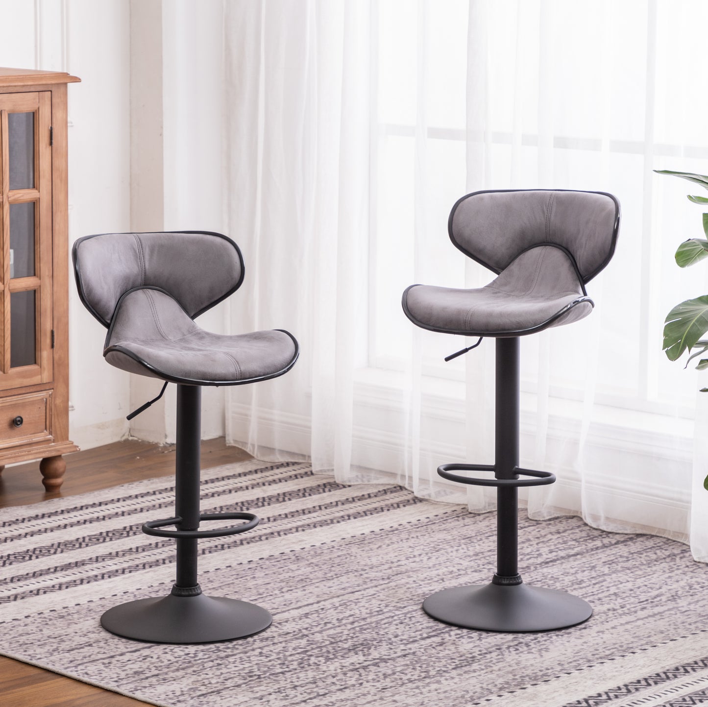 Two grey modern bar stools with black bases and adjustable height on a patterned rug
