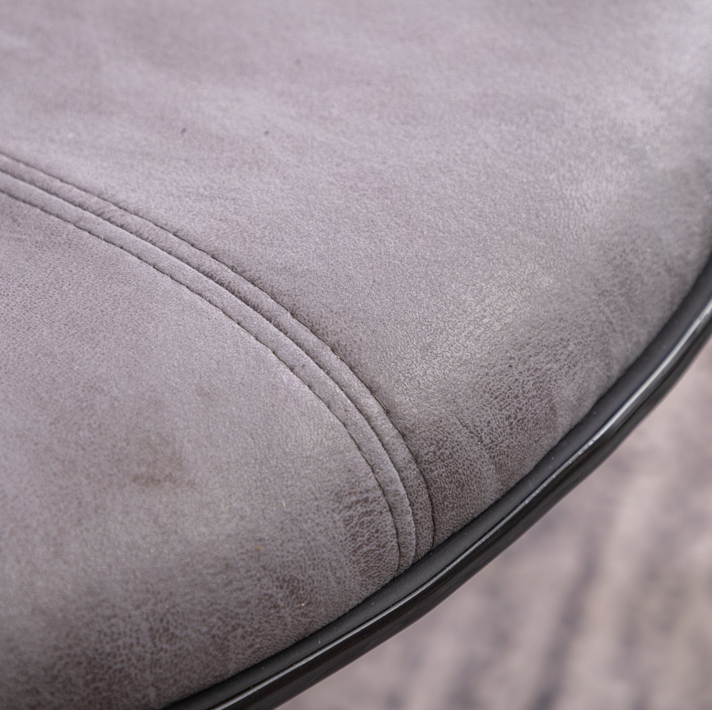 Closeup of a grey faux leather seat cushion with subtle stitching details