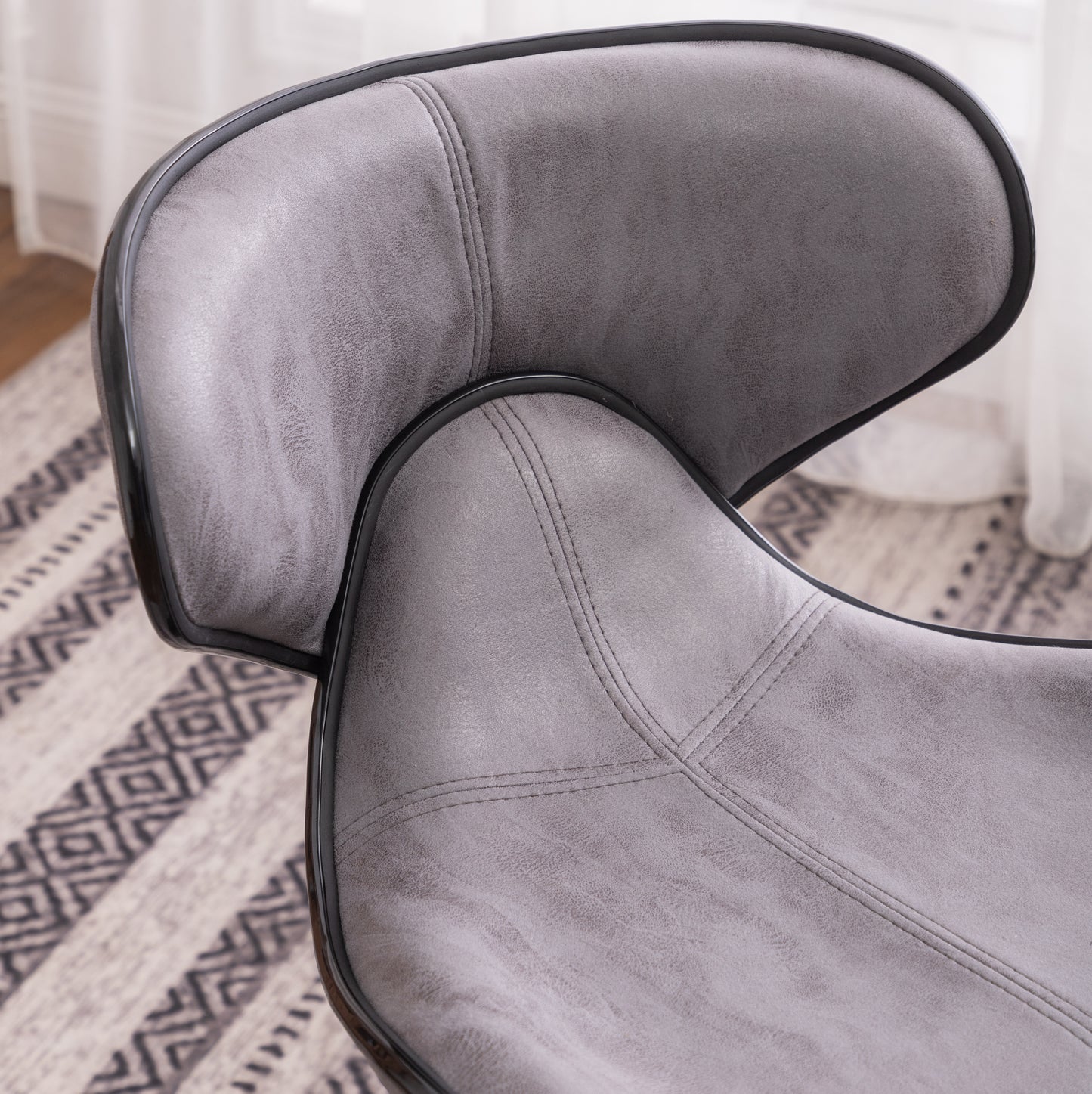Closeup of a grey upholstered dining chair with black trim and stitched detailing