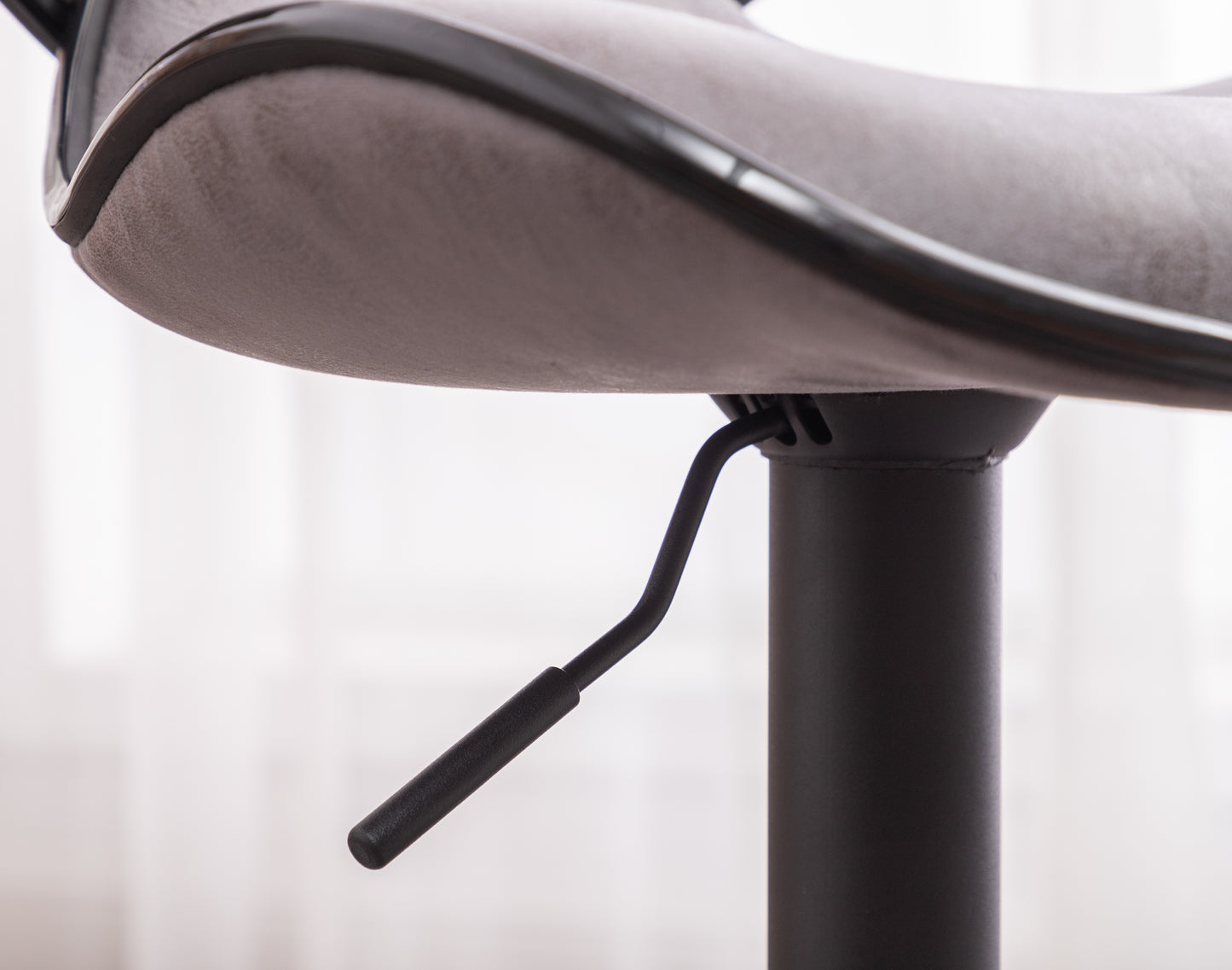 Closeup of a grey suede bar stool seat with black trim and height adjustment lever