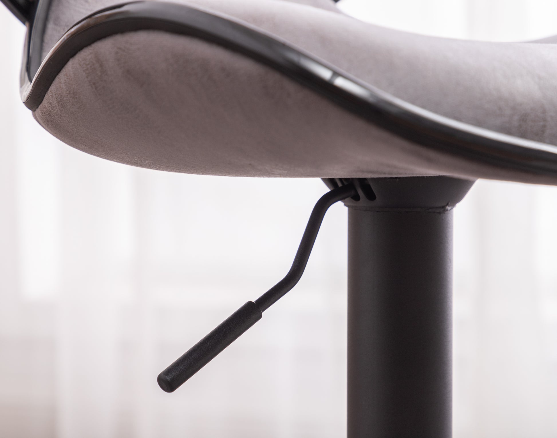 Closeup of a grey suede bar stool seat with black trim and height adjustment lever