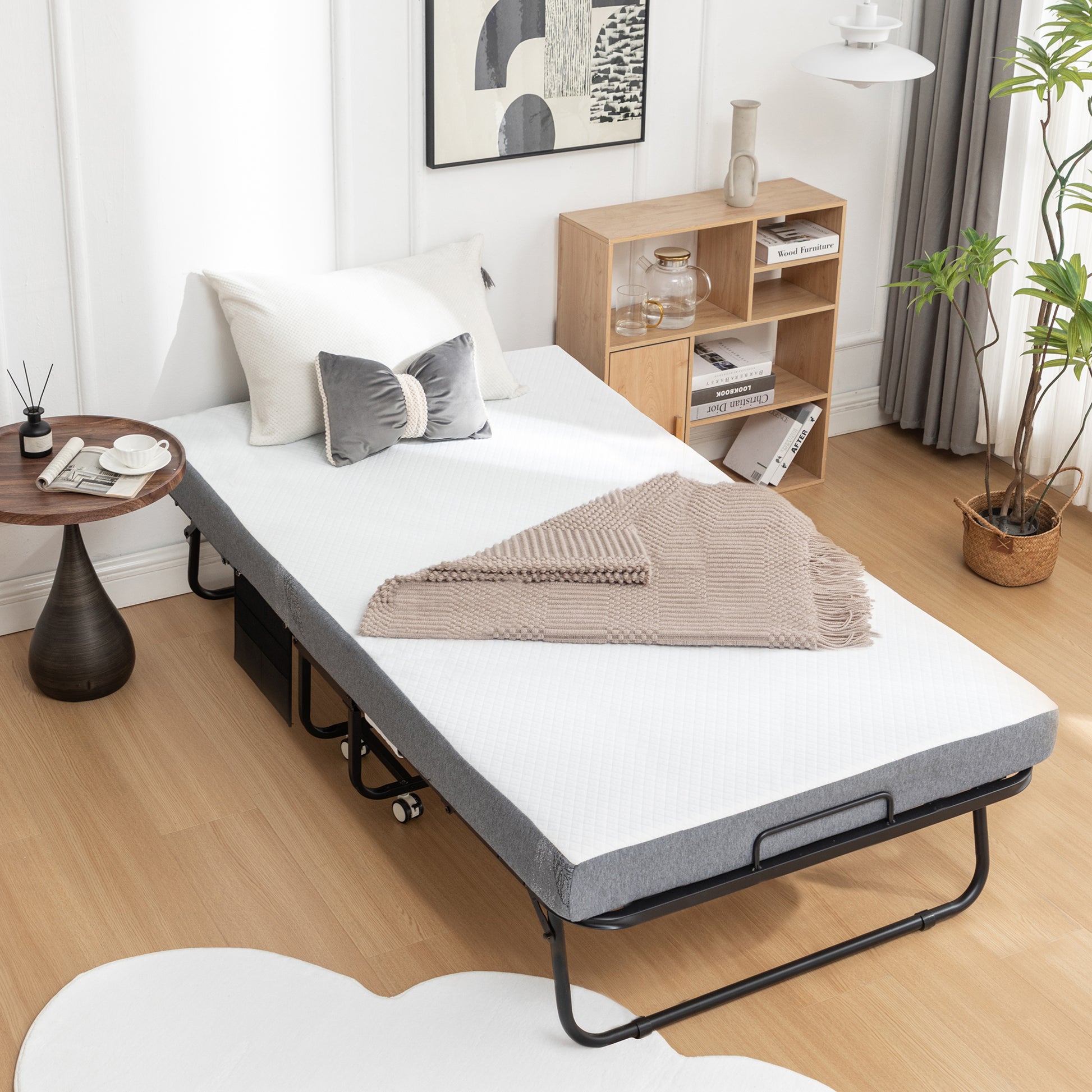 White folding bed with grey frame and beige throw blanket