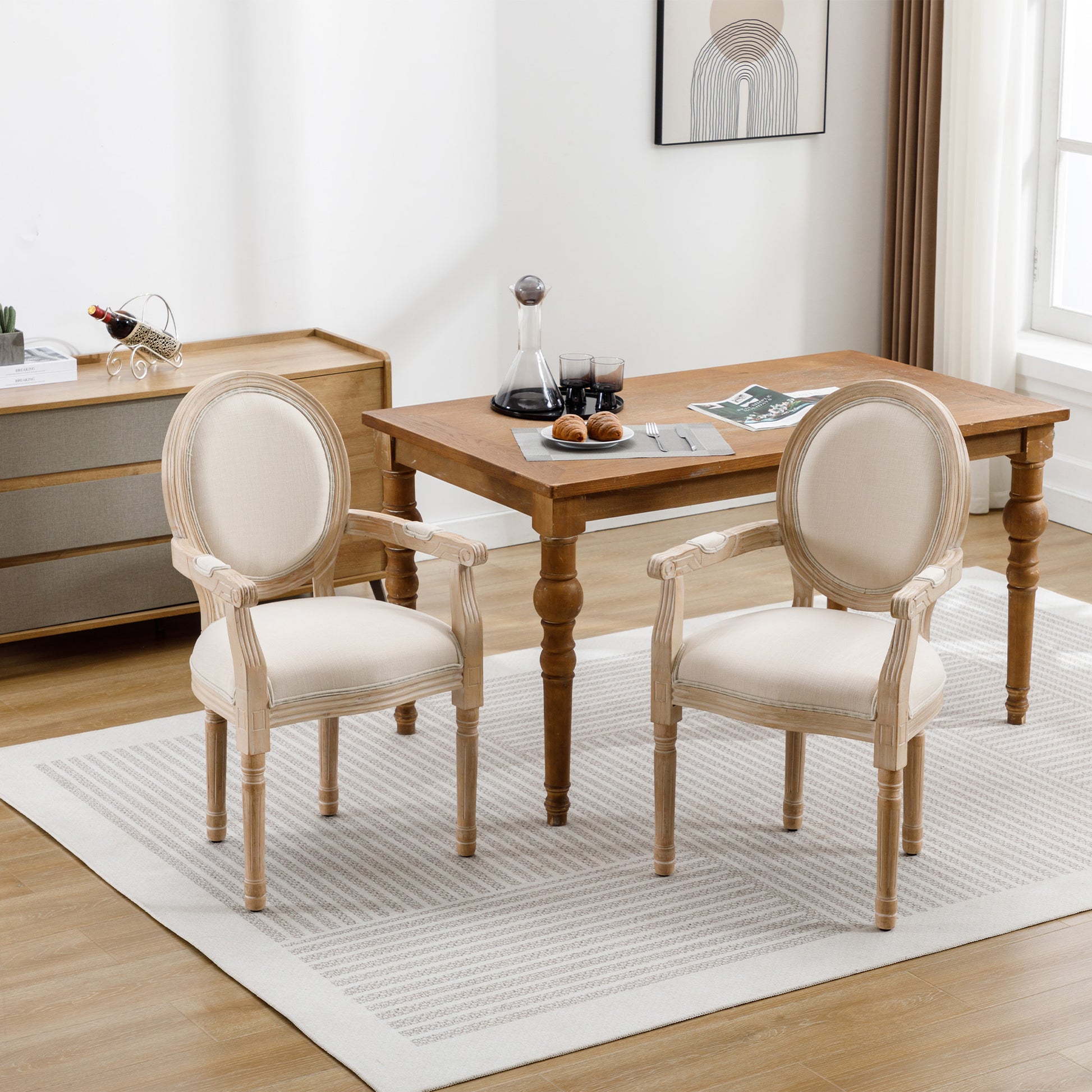 Two ovalback dining chairs with light beige upholstery and whitewashed wood frames