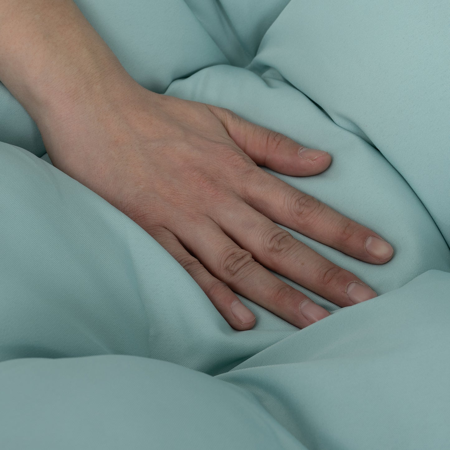 Hand resting on soft light teal fabric with visible texture