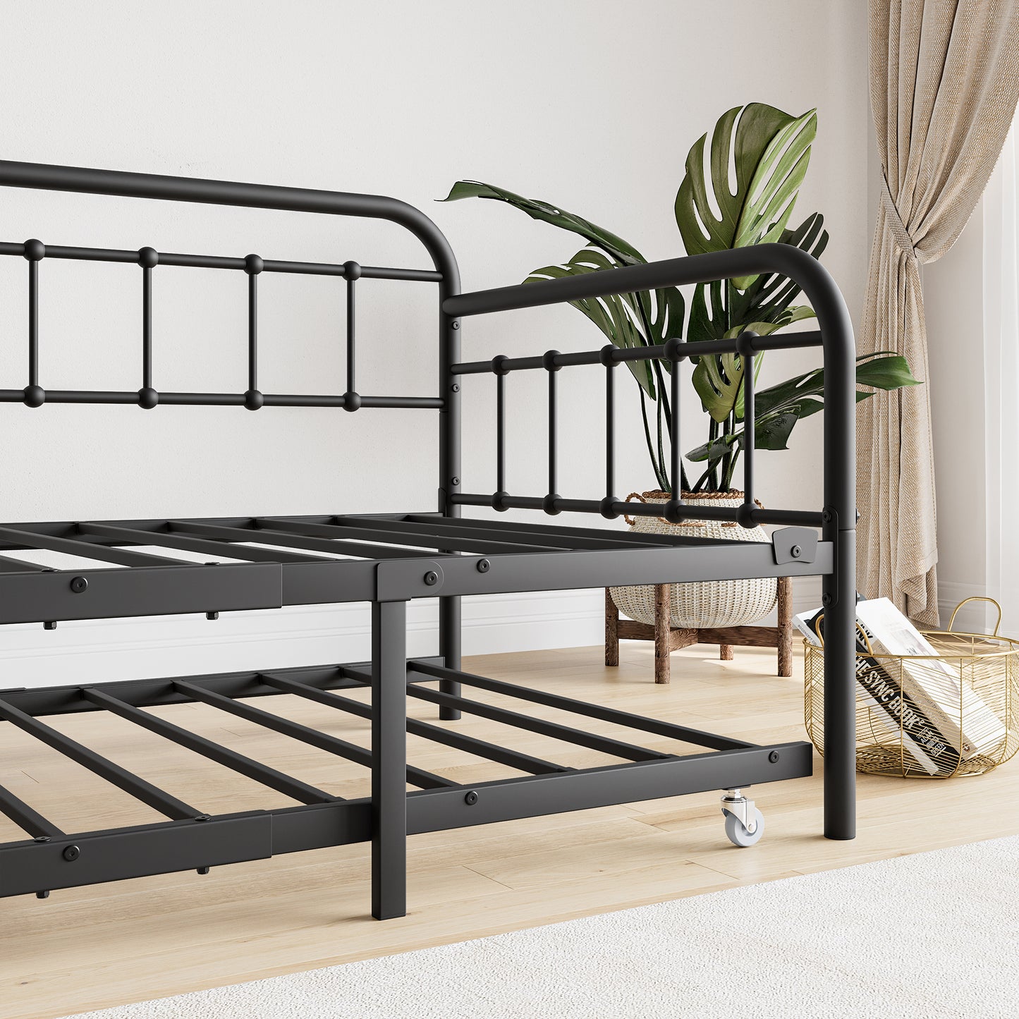 Black metal twin daybed with caster wheels and intricate frame detail
