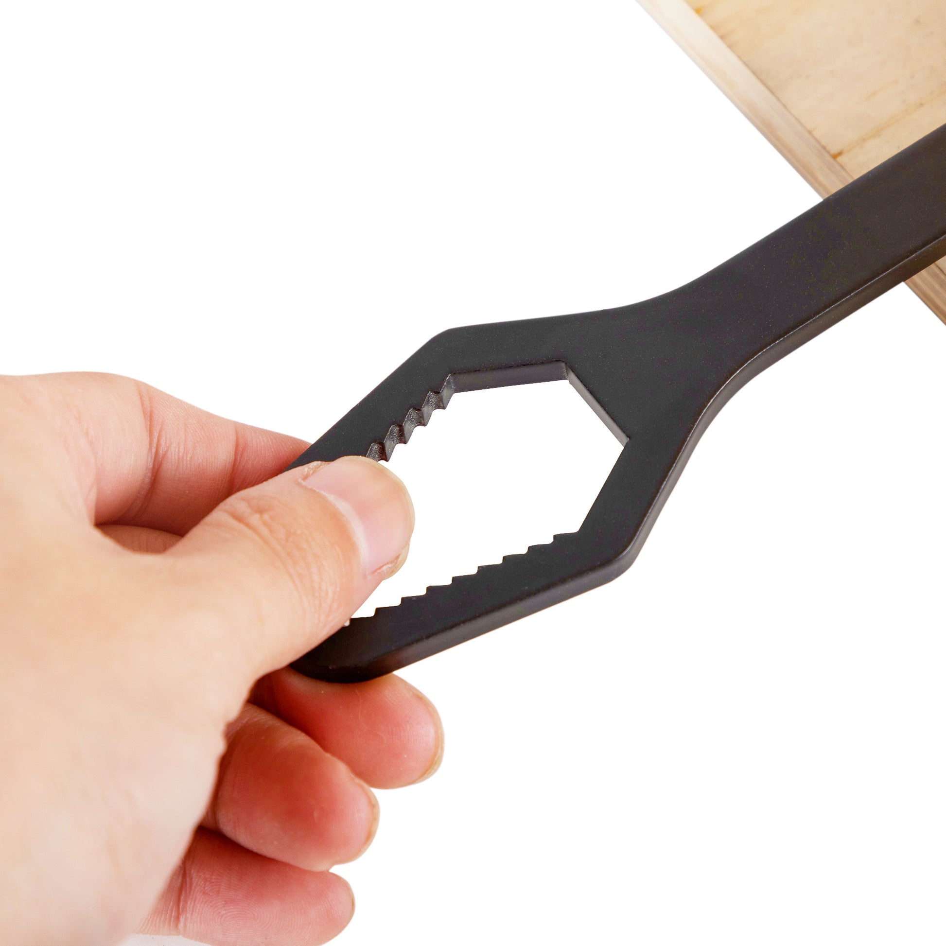 Black selfadjusting wrench with hexagonal opening and serrated edges held by a hand