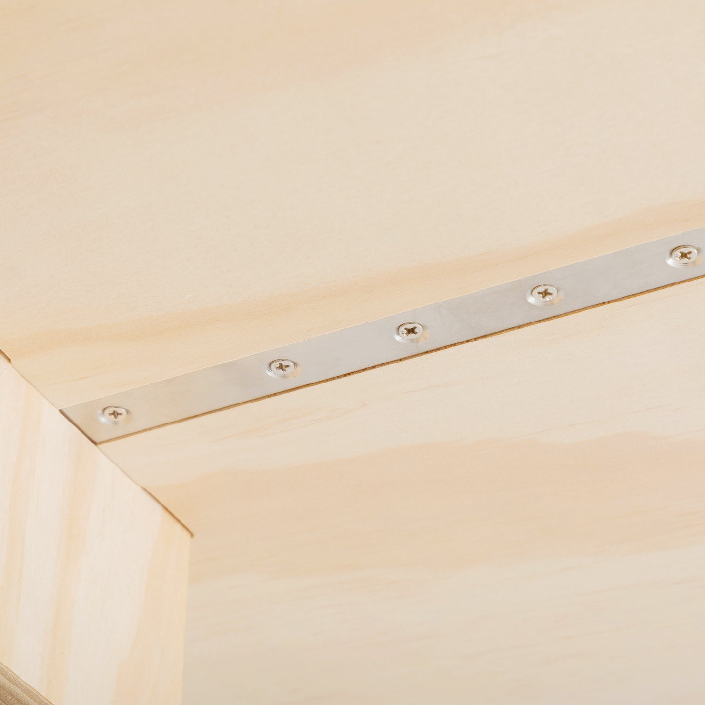 Closeup of a brushed metal brace with silver screws on light wood ideal for furniture construction