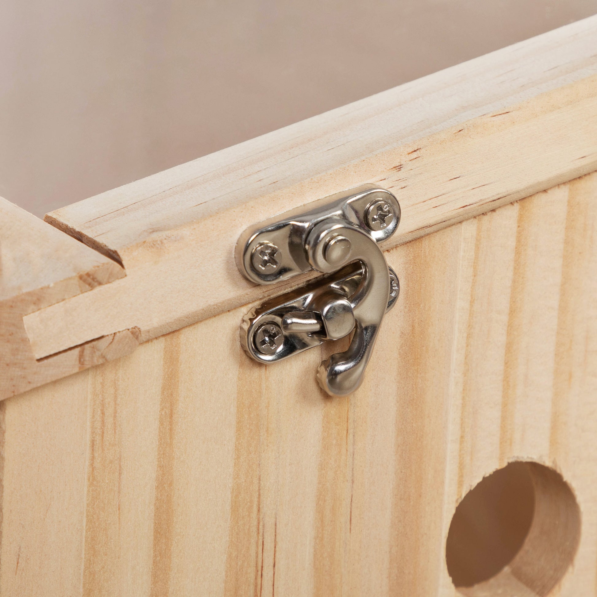 Closeup of a silver latch on a light pine wood box highlighting the hardware detail