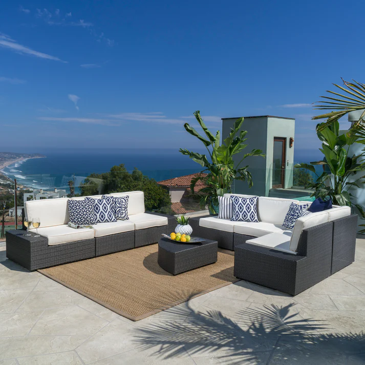 Dark grey wicker sectional outdoor sofa with white cushions and blue patterned pillows