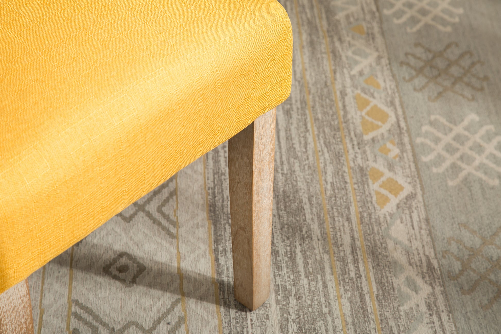 Closeup of bright yellow textured fabric on a wooden leg of a stylish armchair