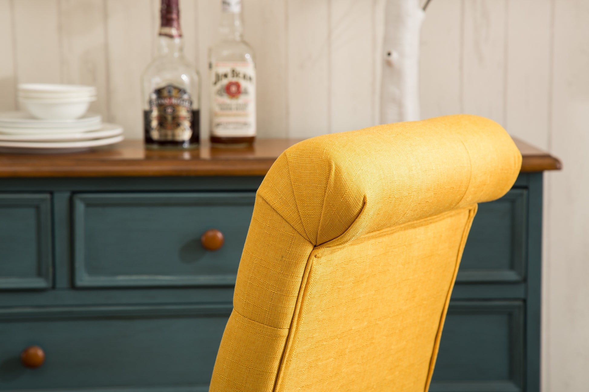 Yellow upholstered dining chair with button tufting on the backrest