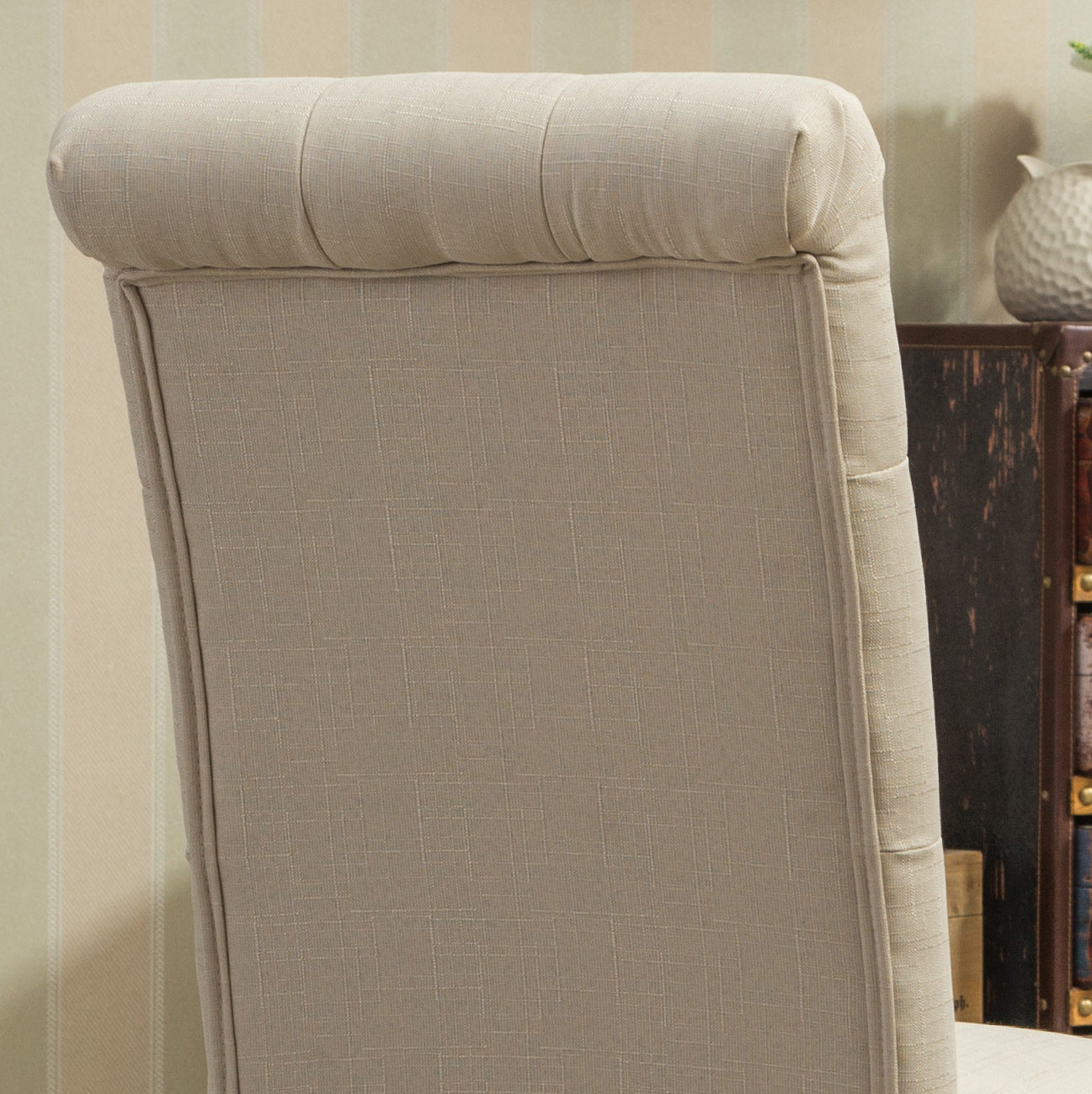 Taupe upholstered chair back with subtle diamond pattern and button tufting detail